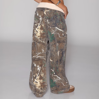 Camouflage pants worn by a person on a plain background